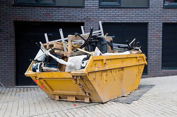 yellow industrial skip full of disused office equipment