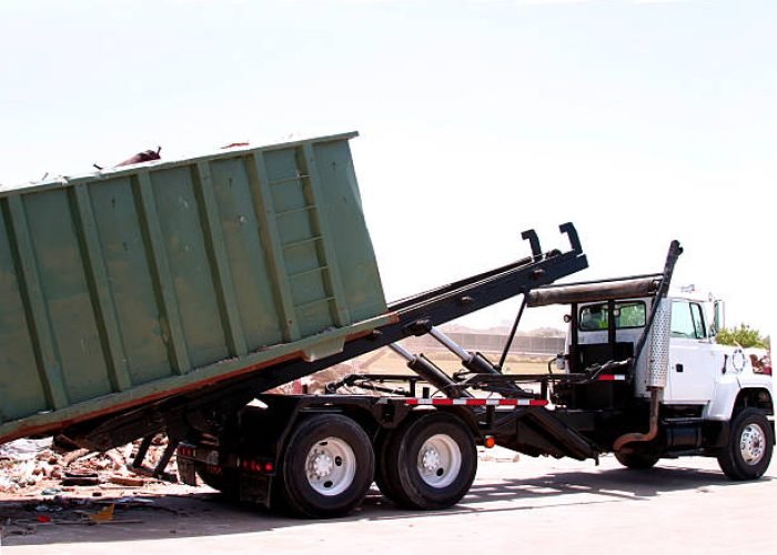 a dumpster loaded with trash is unloaded by a heavy duty truck.